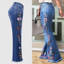 Denimjeans i vintagestil med broderade blommor, vida ben och fransad fåll