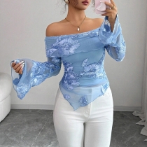 Volangtopp med båtringning, vida ärmar och asymmetrisk broderidetalj i nederkant